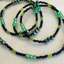 Set of beaded necklaces with green and black beads on a light background