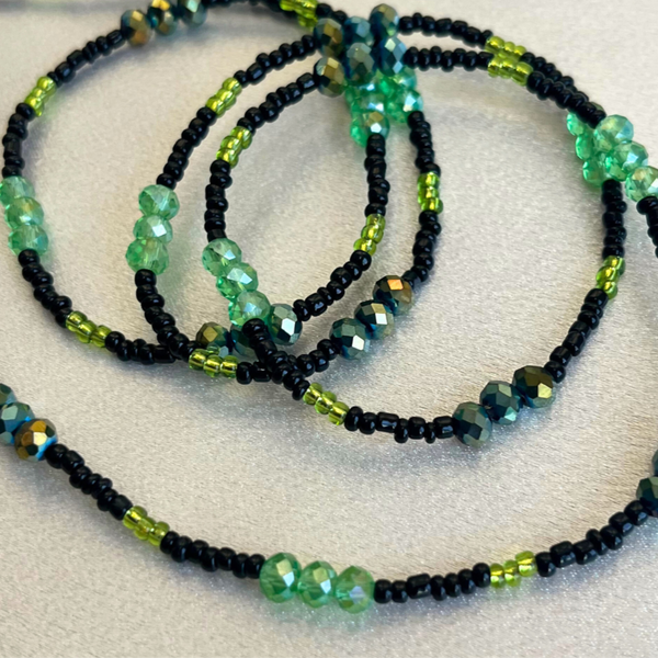 Set of beaded necklaces with green and black beads on a light background