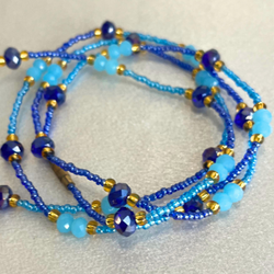 Blue beaded necklace with gold accents on a beige background.