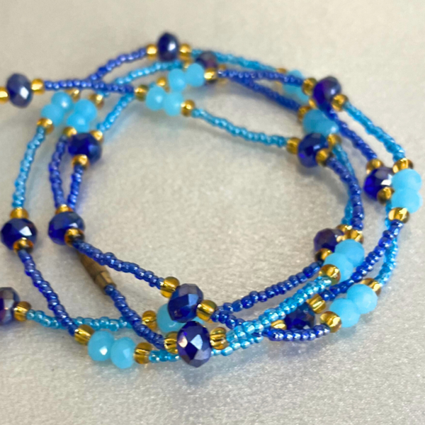 Blue beaded necklace with gold accents on a beige background.